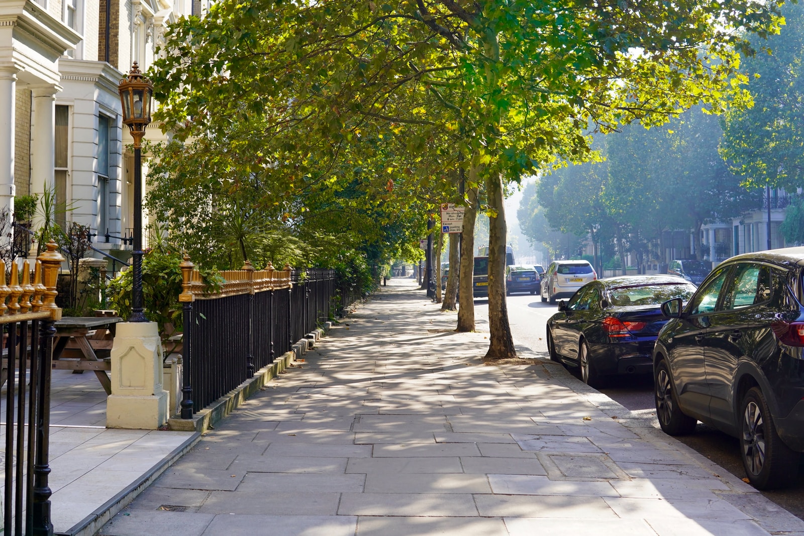 cars parked on sidewalk near trees during daytime