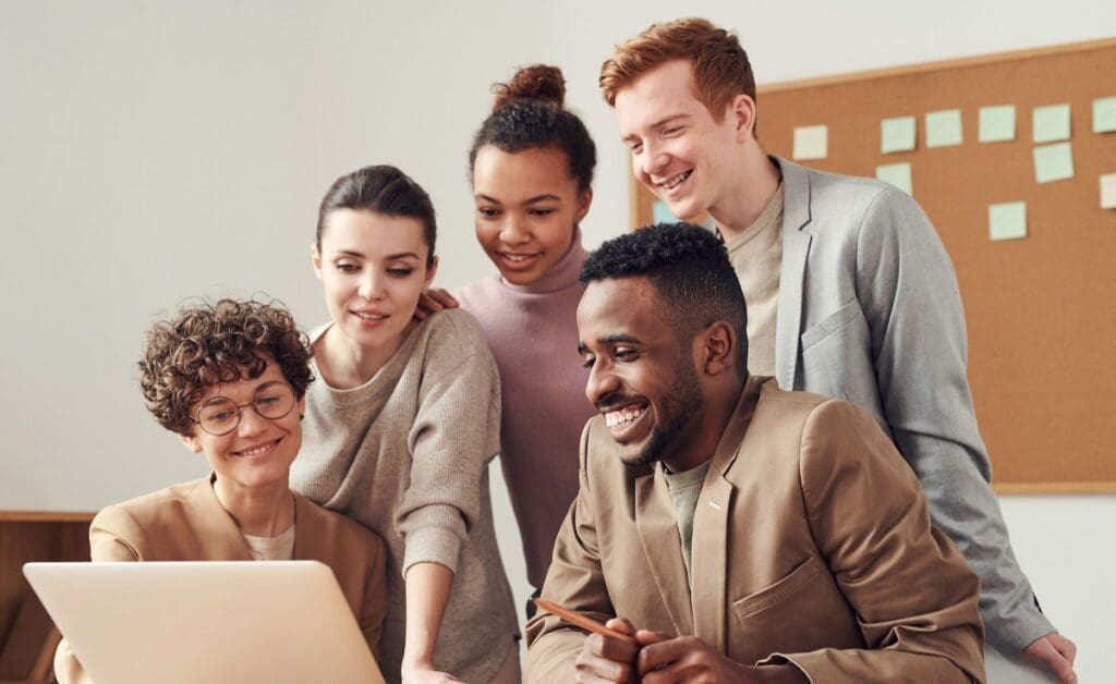 Four colleagues gathered around a laptop in an office